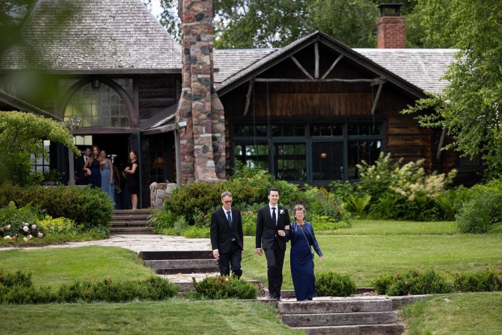 Brittany and Cole walking towards Stout’s Island Lodge boat house, Wisconsin wedding photography.