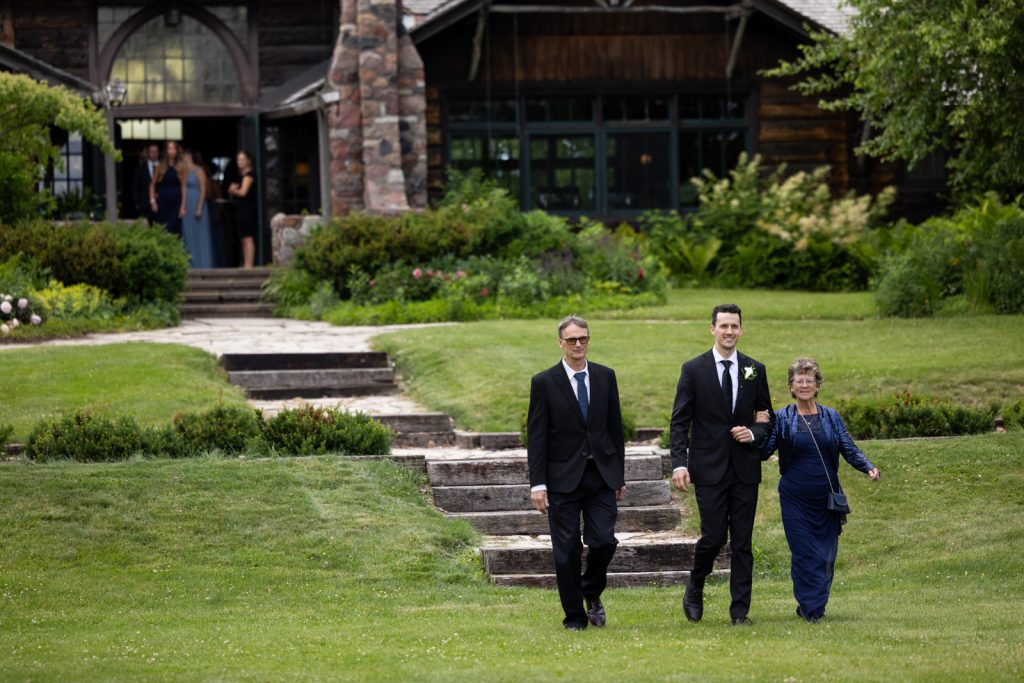 Brittany and Cole's Stout’s Island wedding party walking down stone steps toward the lodge.