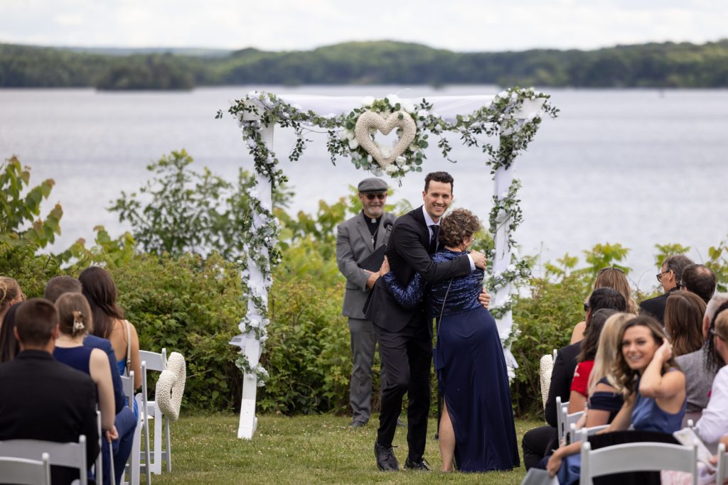 Brittany and Cole wedding ceremony on Stout’s Island, Wisconsin, with decorated archway and lakeside view.