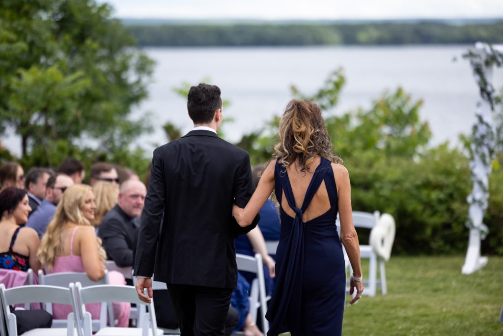 Bride and groom walking away from wedding ceremony on Stout’s Island, Red Cedar Lake, Wisconsin.
