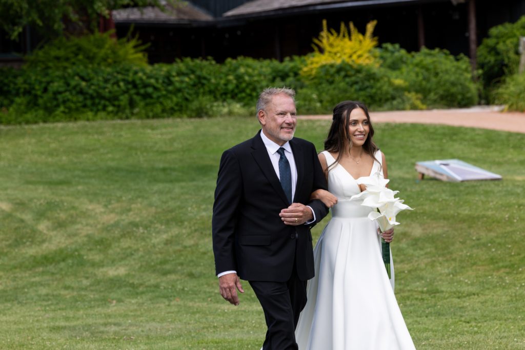 Bride and father walking on Stout’s Island lawn during Wisconsin wedding ceremony