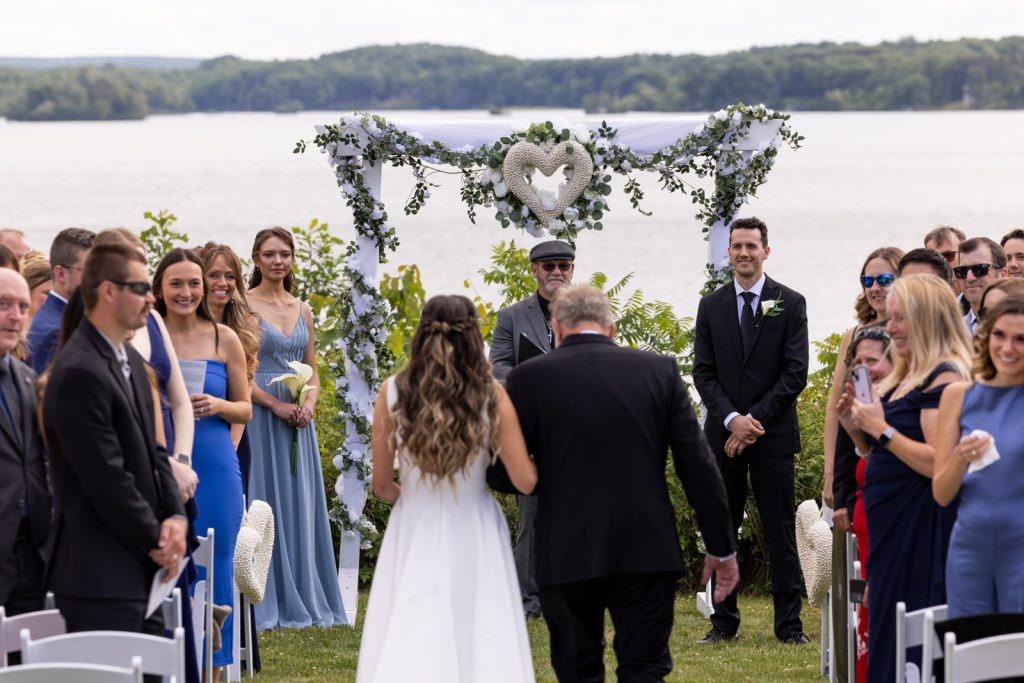 Stout’s Island wedding ceremony with floral arch and lake backdrop.