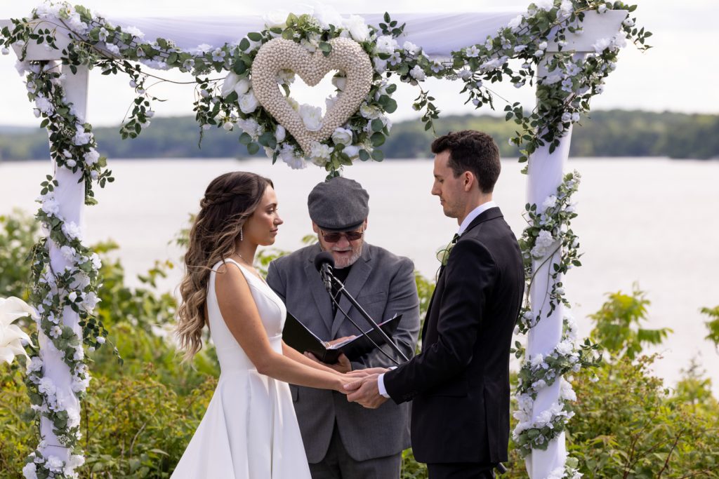 Brittany and Cole wedding ceremony on Stout’s Island, Wisconsin, with floral arch and lake view