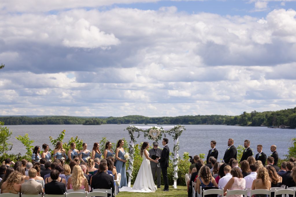 Brittany and Cole exchanging vows at Stout’s Island wedding ceremony, Red Cedar Lake backdrop