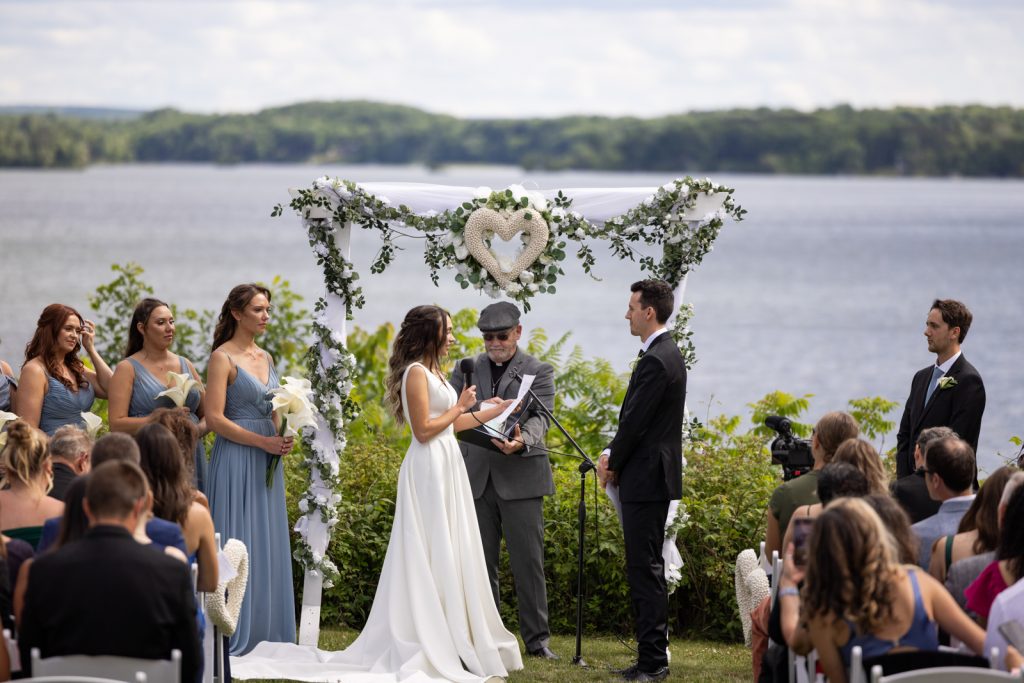 Stout’s Island wedding ceremony with floral arch and lake backdrop in Birchwood, Wisconsin.