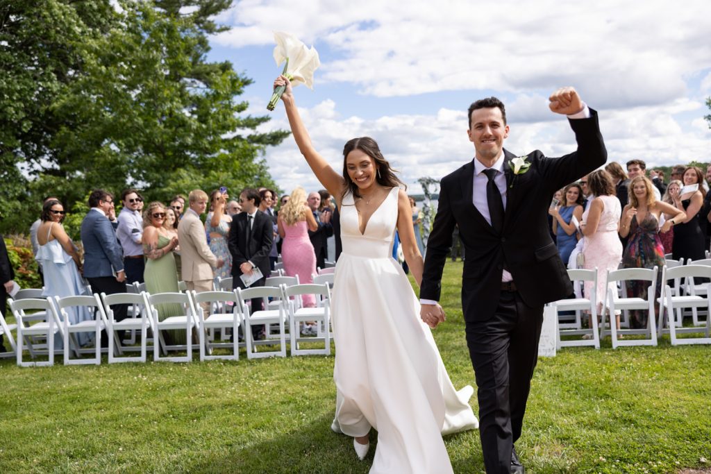 Brittany and Cole celebrating their Stout’s Island wedding, walking through the grassy ceremony area.
