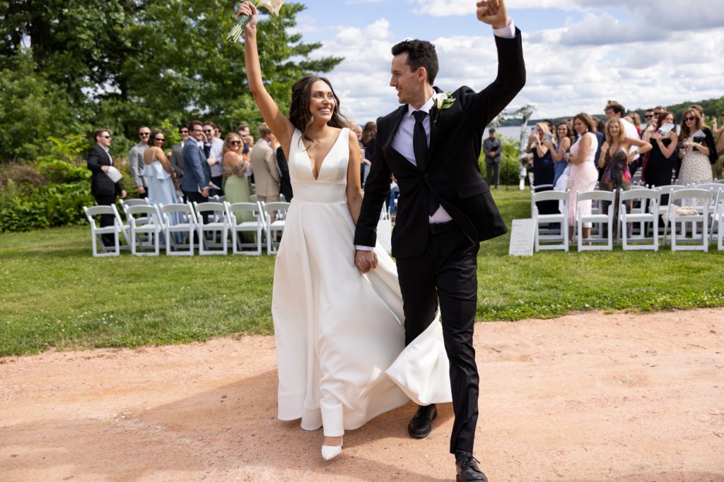Brittany and Cole celebrating their wedding on Stout’s Island, Wisconsin, with guests in the background.