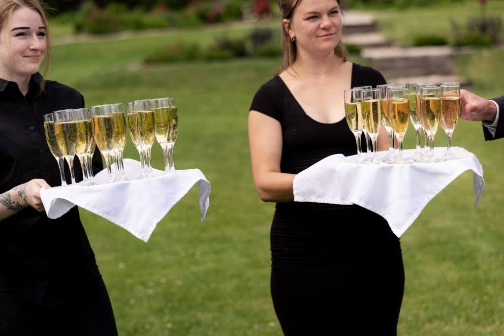 Wedding staff serving champagne flutes on Stout’s Island in Wisconsin.