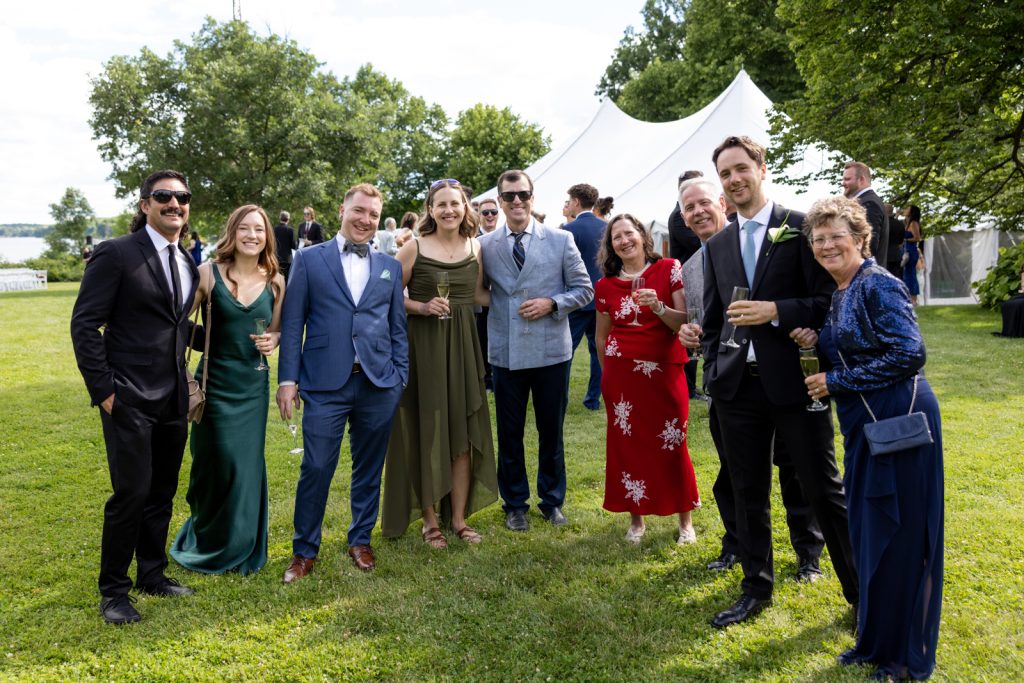 Brittany and Cole's wedding party gathered on Stout’s Island lawn, celebrating with champagne near a