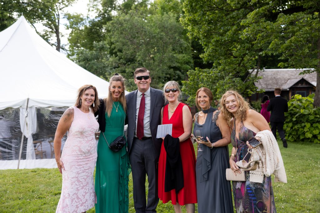 Brittany and Cole’s Stout’s Island wedding guests gathered under a tent on Red Cedar Lake,
