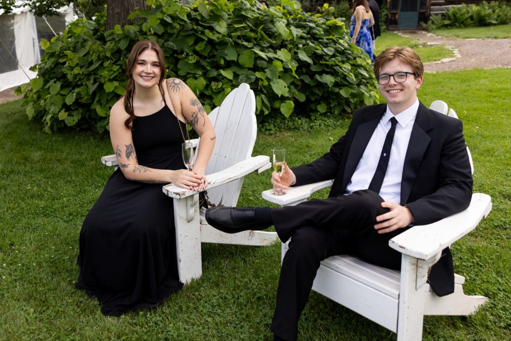 Brittany and Cole, the wedding couple, toasting with champagne in Adirondack chairs at Stout’s Island