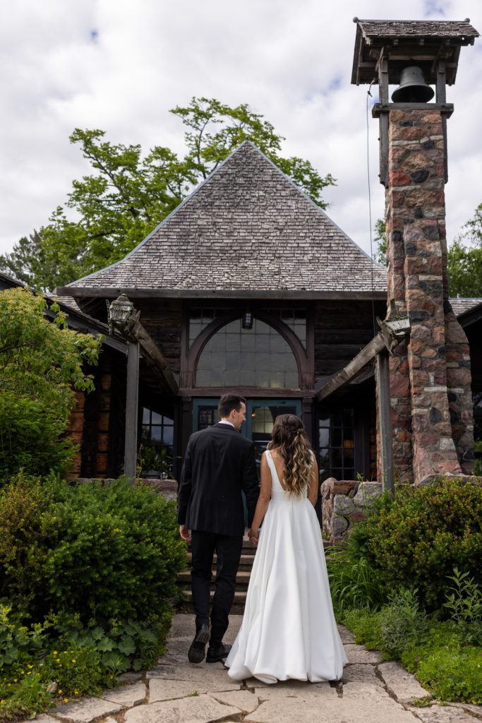 Brittany and Cole walking away from Stout’s Island Lodge boat house, Wisconsin wedding photography.