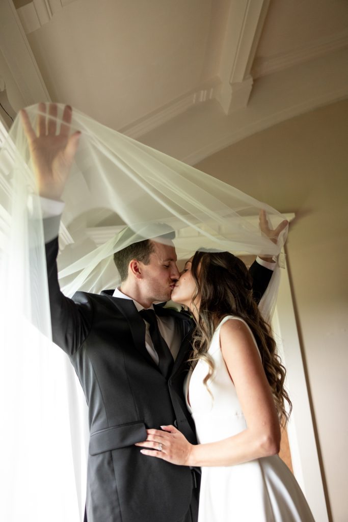 Brittany and Cole kissing under a veil at Stout’s Island wedding in Birchwood, Wisconsin.