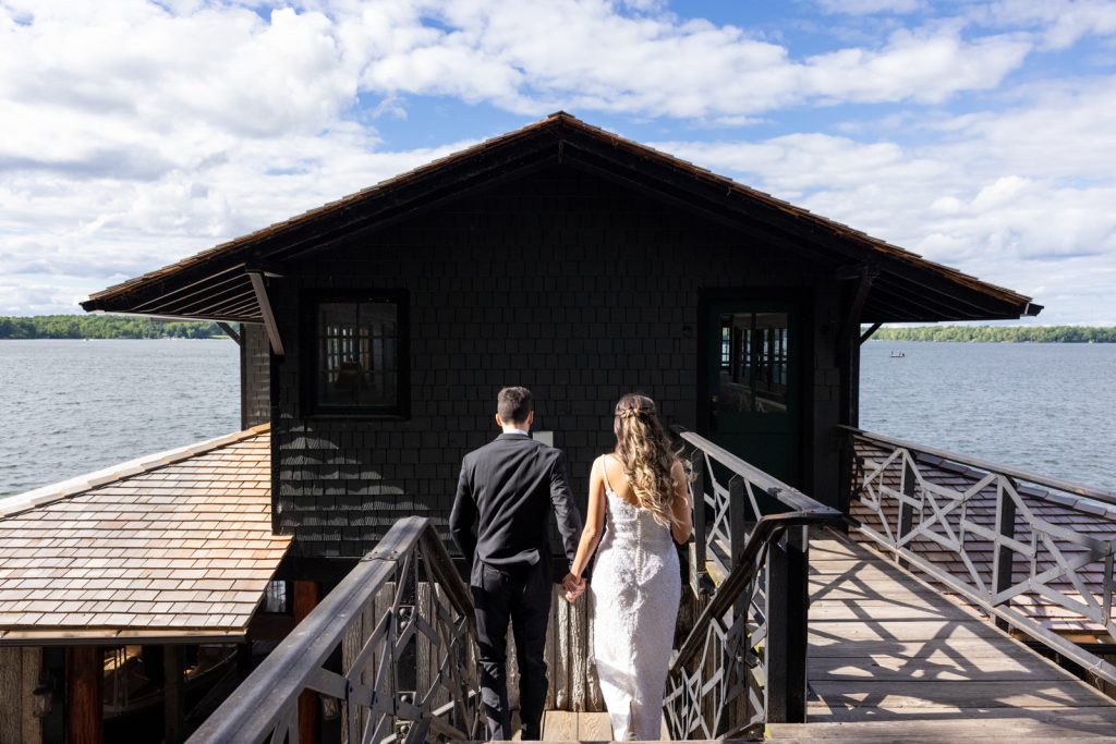 Brittany and Cole, wedding couple, walking away from Stout’s Island Lodge boat house on Red