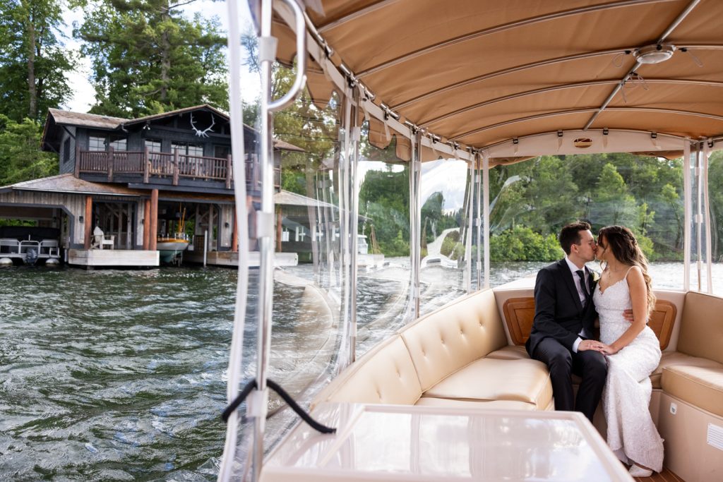 Bride and groom kissing on boat arriving at Stout’s Island Lodge, Birchwood, Wisconsin wedding venue.