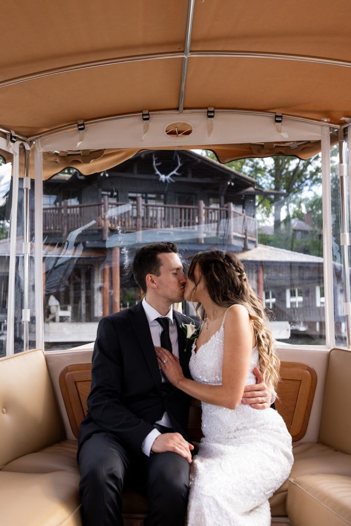 Brittany and Cole kissing in golf cart on Stout’s Island, Wisconsin wedding.