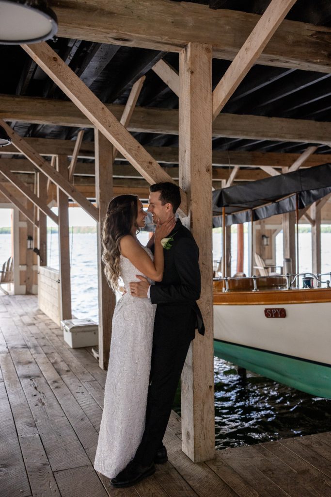 Brittany and Cole embracing under the boat house at Stout’s Island wedding on Red Cedar