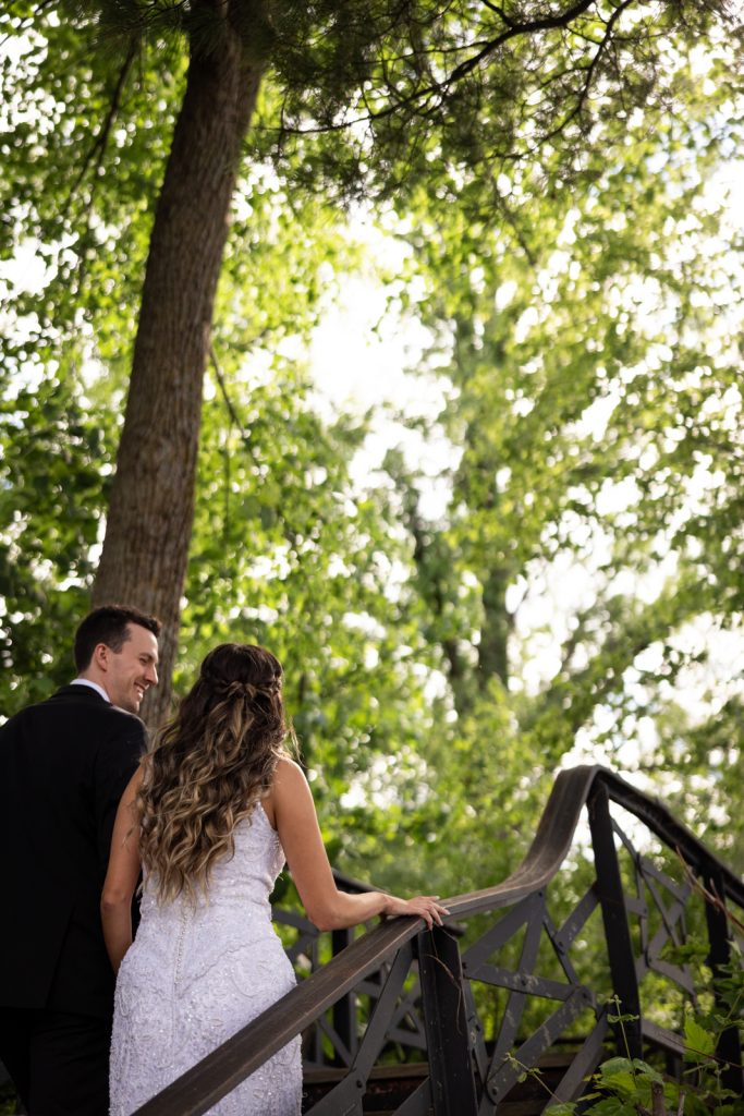 Brittany and Cole, wedding couple on Stout’s Island, Wisconsin, walking on a bridge overlooking Red