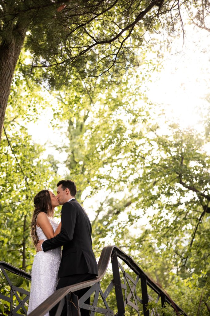 Brittany and Cole kissing on Stout’s Island wedding day, surrounded by lush greenery and sunlight.