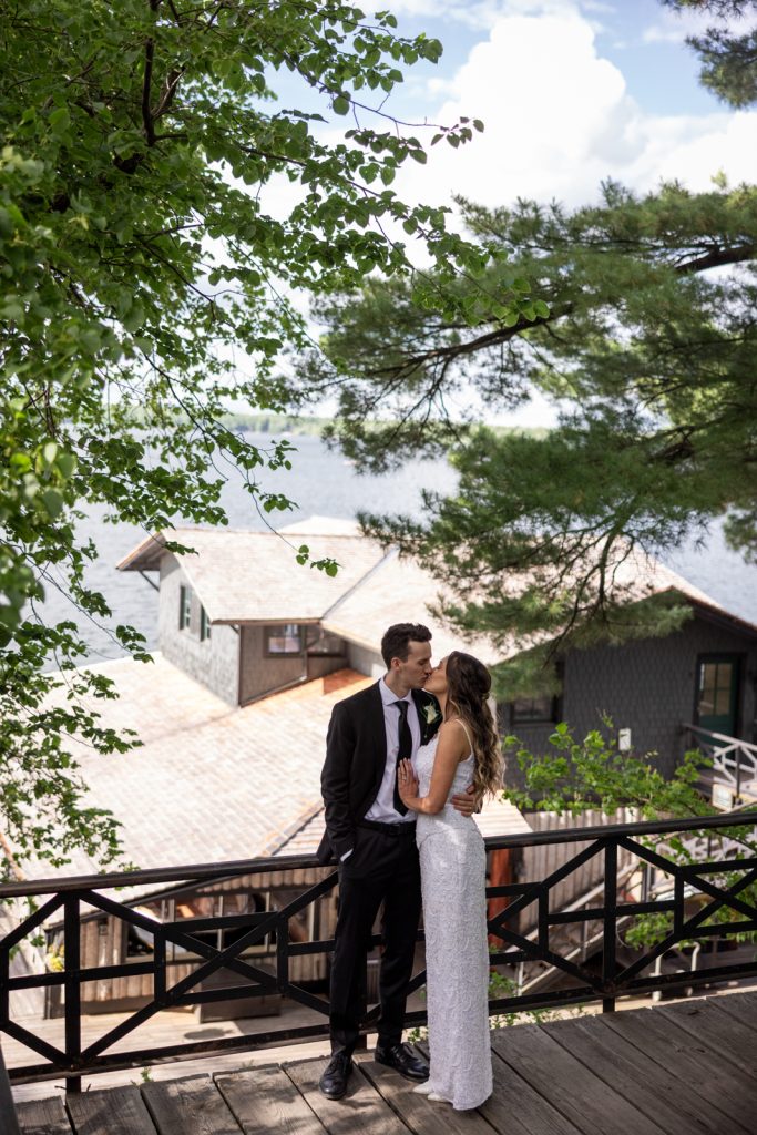 Brittany and Cole kissing on Stout’s Island Lodge balcony overlooking Red Cedar Lake, Wisconsin wedding