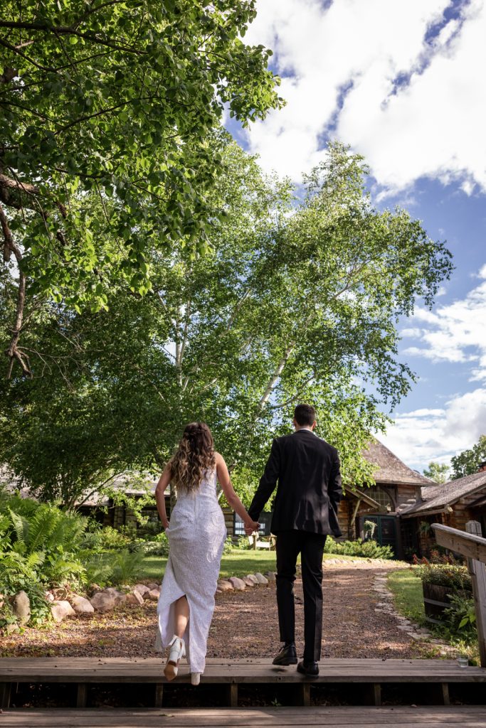 Brittany and Cole walking hand-in-hand on Stout’s Island, Wisconsin wedding venue.