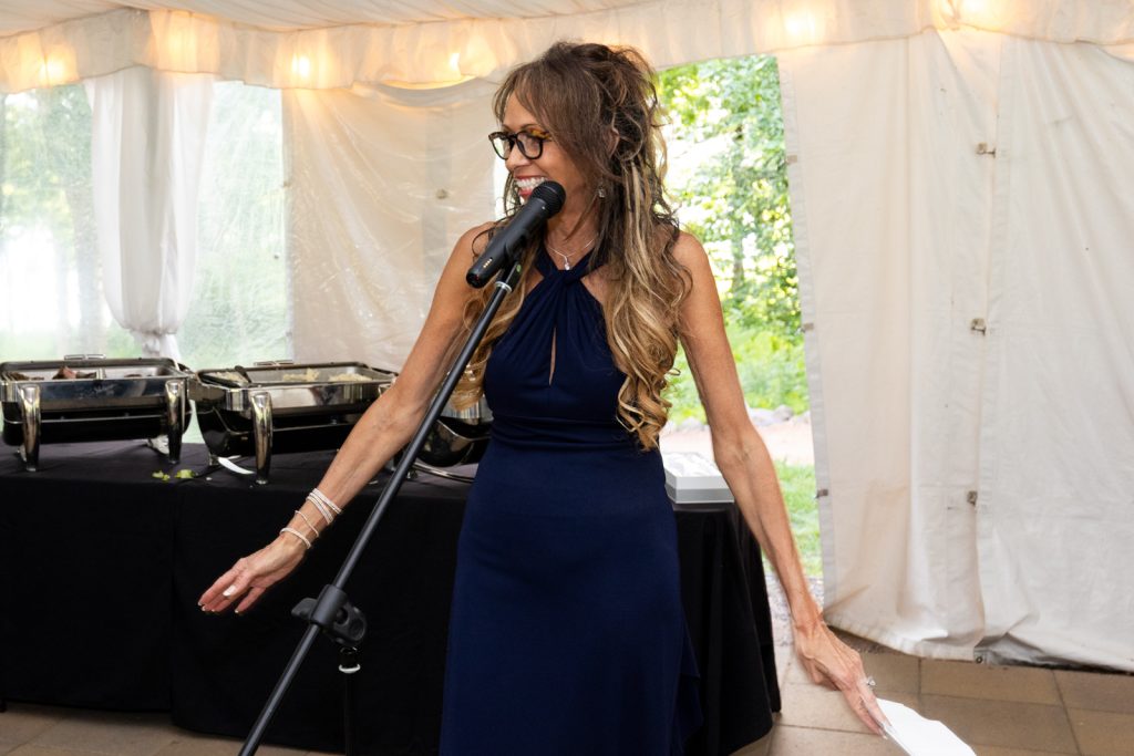 Bride speaking into microphone at Stout’s Island wedding reception in Birchwood, Wisconsin.