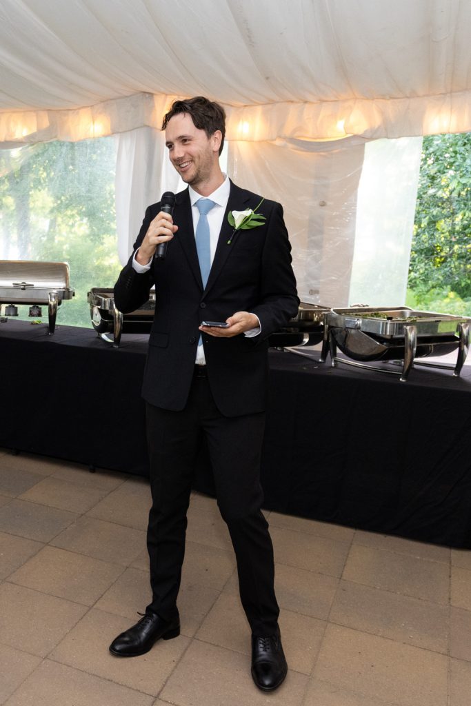Groom speaking into microphone at Stout’s Island wedding reception in Birchwood, Wisconsin.