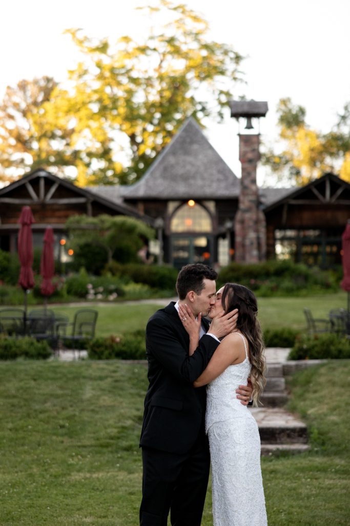 Brittany and Cole kissing in front of Stout’s Island Lodge boathouse, Wisconsin wedding photography.