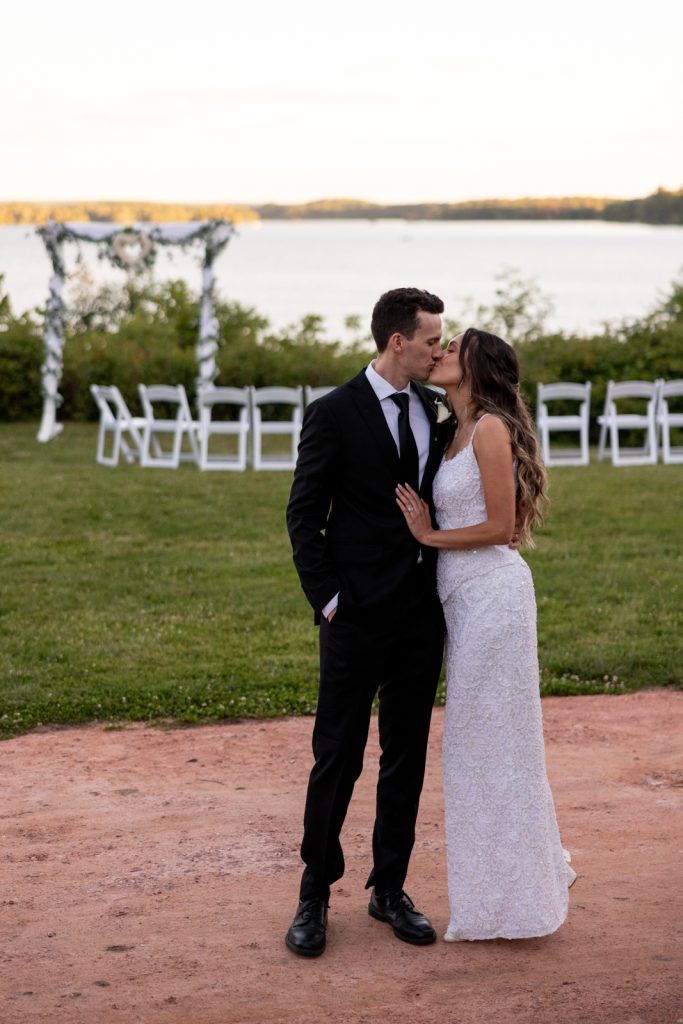 Brittany and Cole sharing a kiss at their Stout’s Island wedding ceremony on Red Cedar