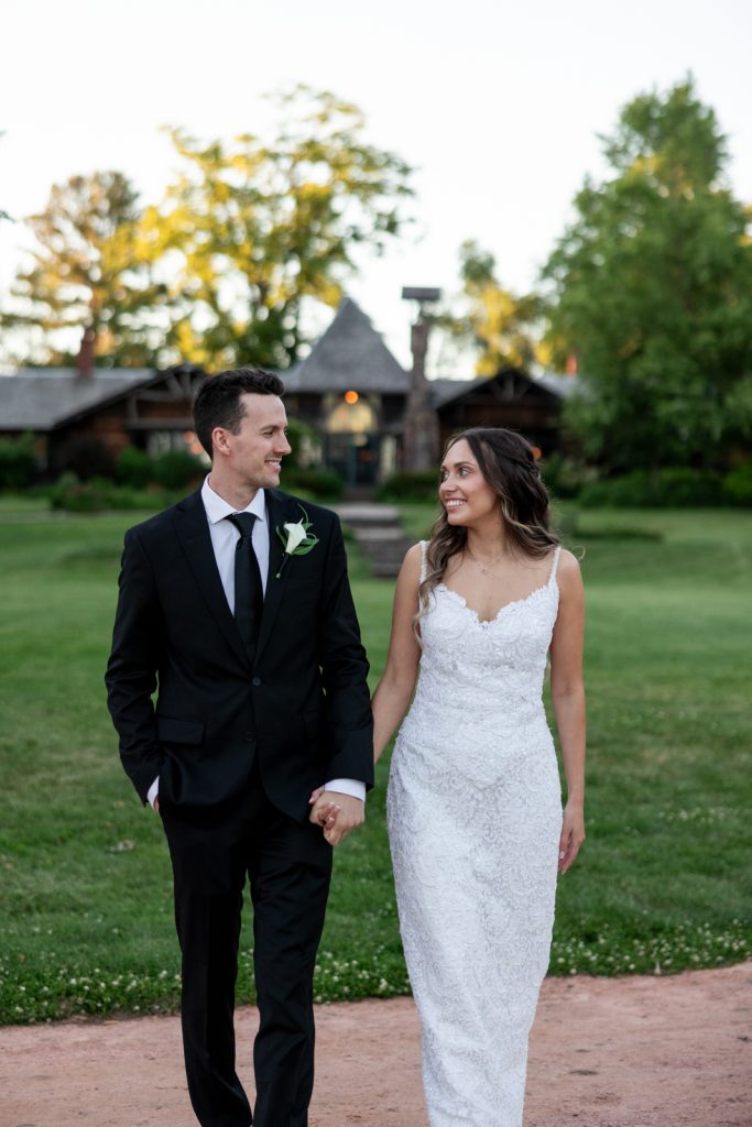 Brittany and Cole, wedding couple, smiling and holding hands at Stout’s Island Lodge in Birchwood,