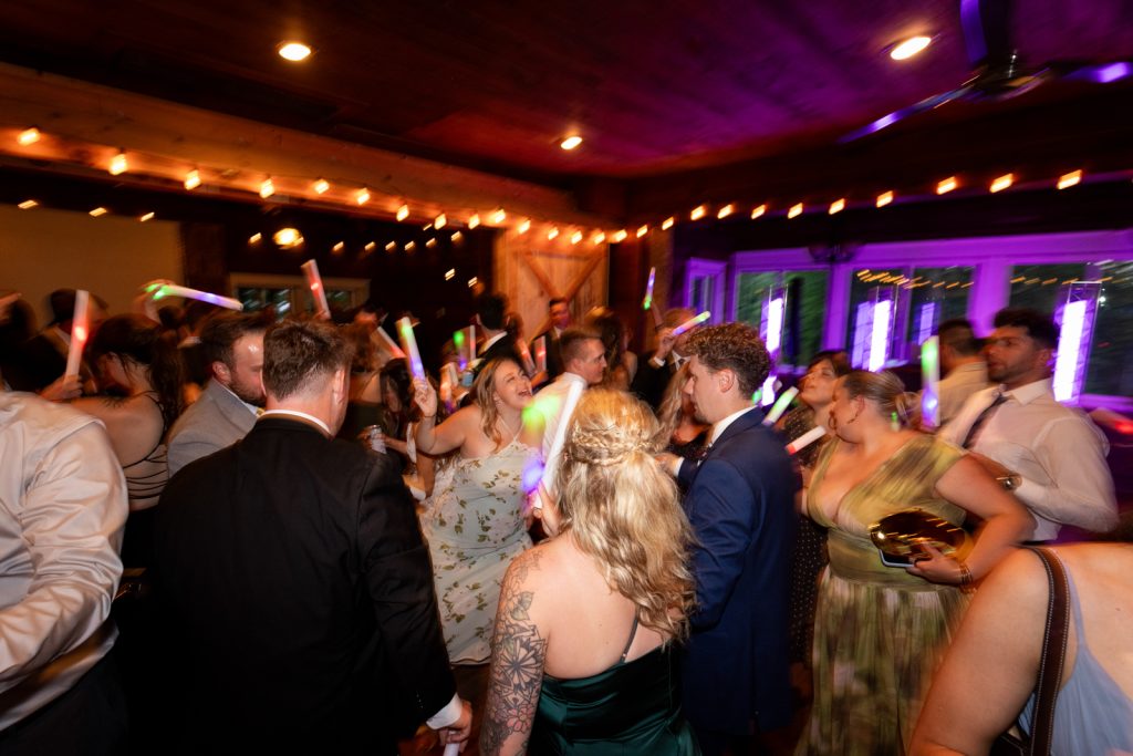 Wedding reception at Stout’s Island Lodge, Birchwood, Wisconsin, with guests dancing and waving glow sticks.