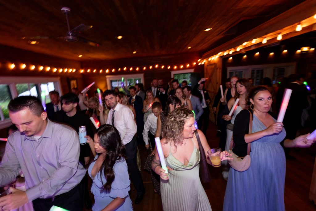 Wedding reception at Stout’s Island Lodge, Birchwood, Wisconsin, with guests dancing and holding glow sticks.