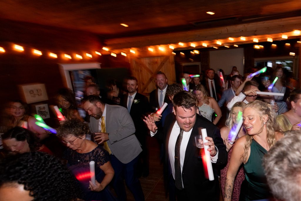 Wedding reception celebration at Stout’s Island Lodge with guests and glow sticks.