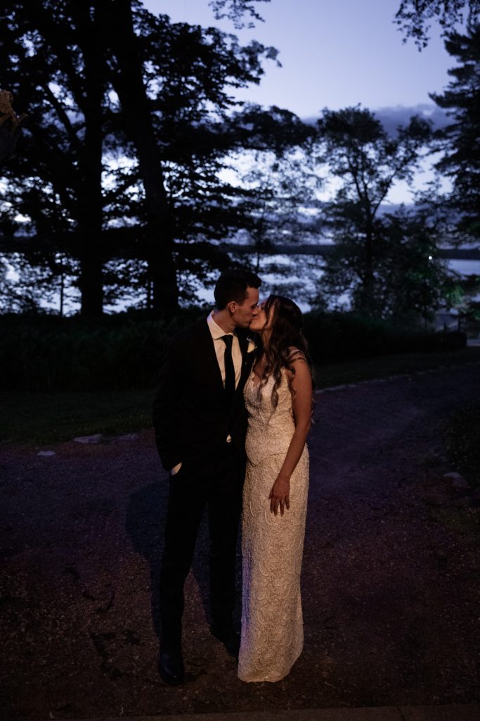 Brittany and Cole kissing at Stout’s Island wedding in Birchwood, Wisconsin, lakeside scene.