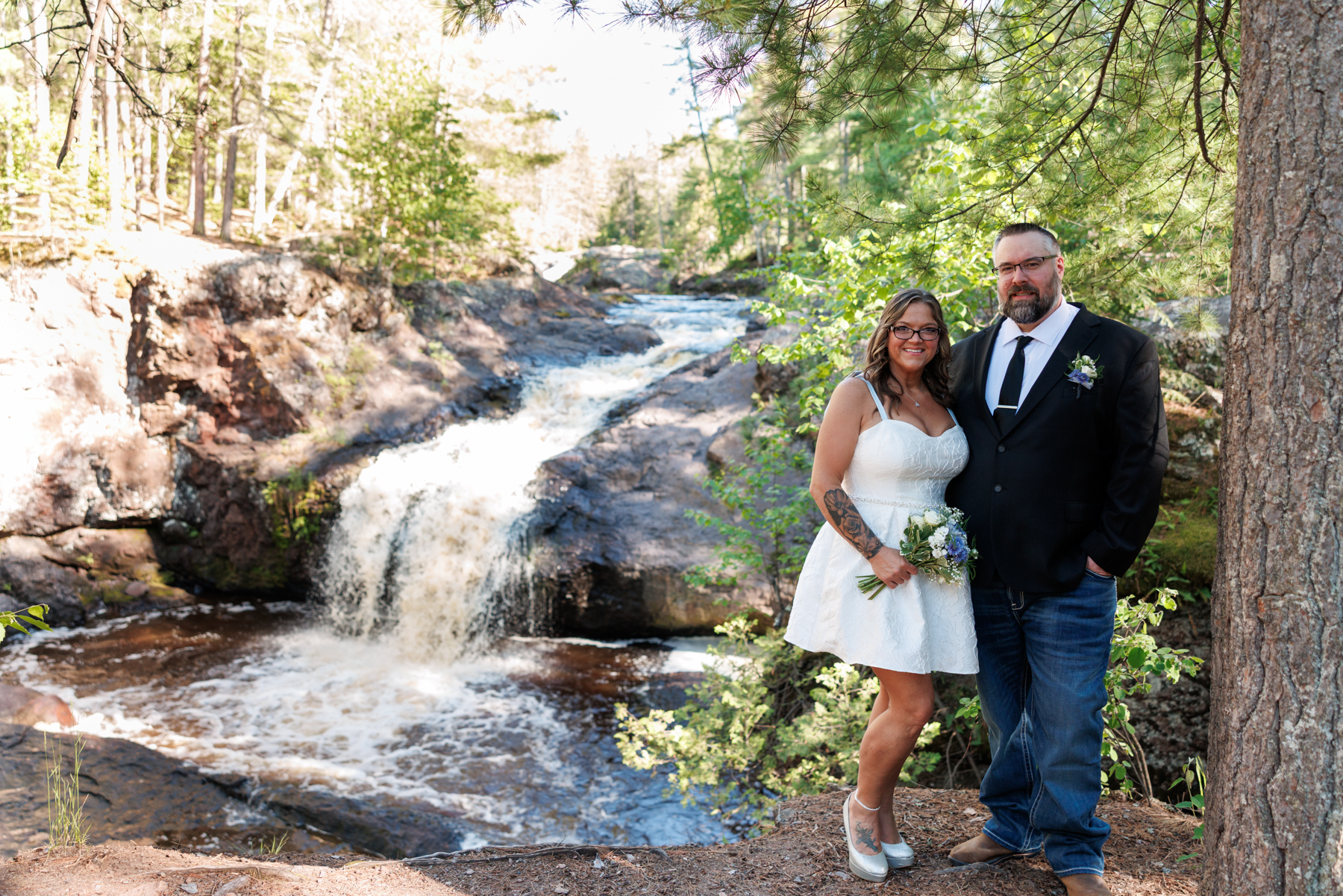 Bride and groom posing near Amnicon Falls waterfall, Wisconsin wedding photography.