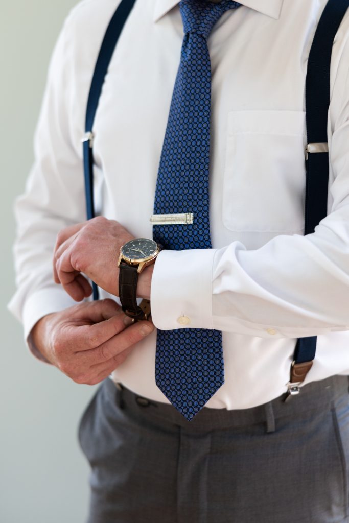 Groom adjusting watch and tie at Hayward, WI wedding.