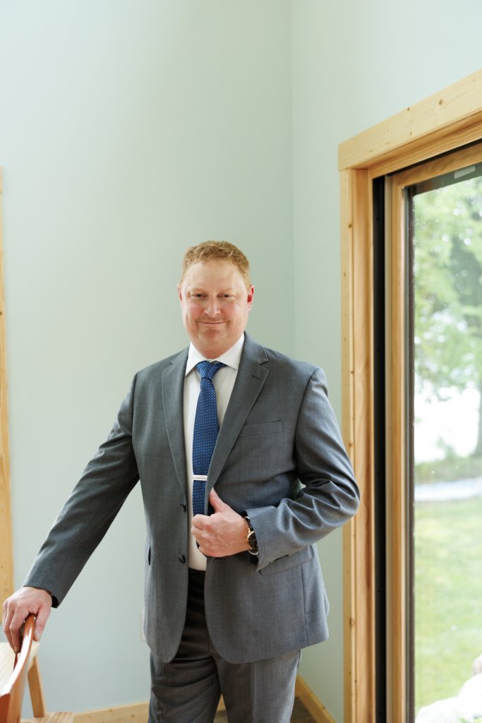 Groom in suit adjusting jacket, Hayward, WI wedding photography.