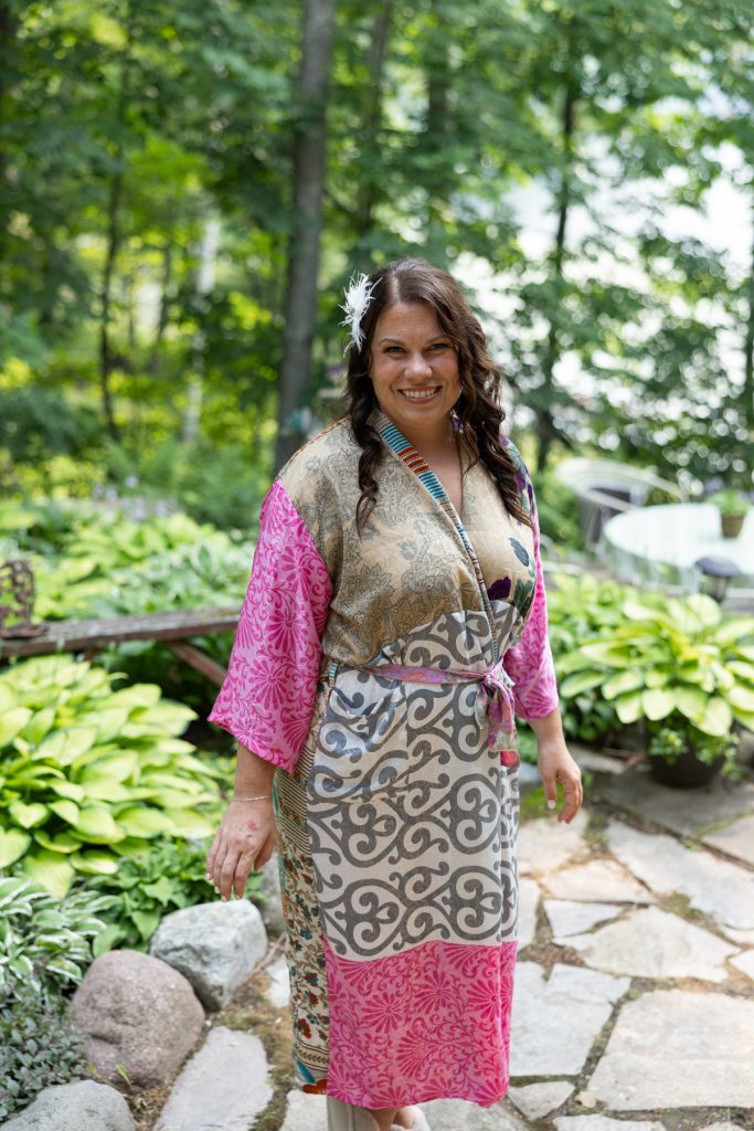 Bride in pink and gold kimono smiling at lakeside cabin wedding in Hayward, WI