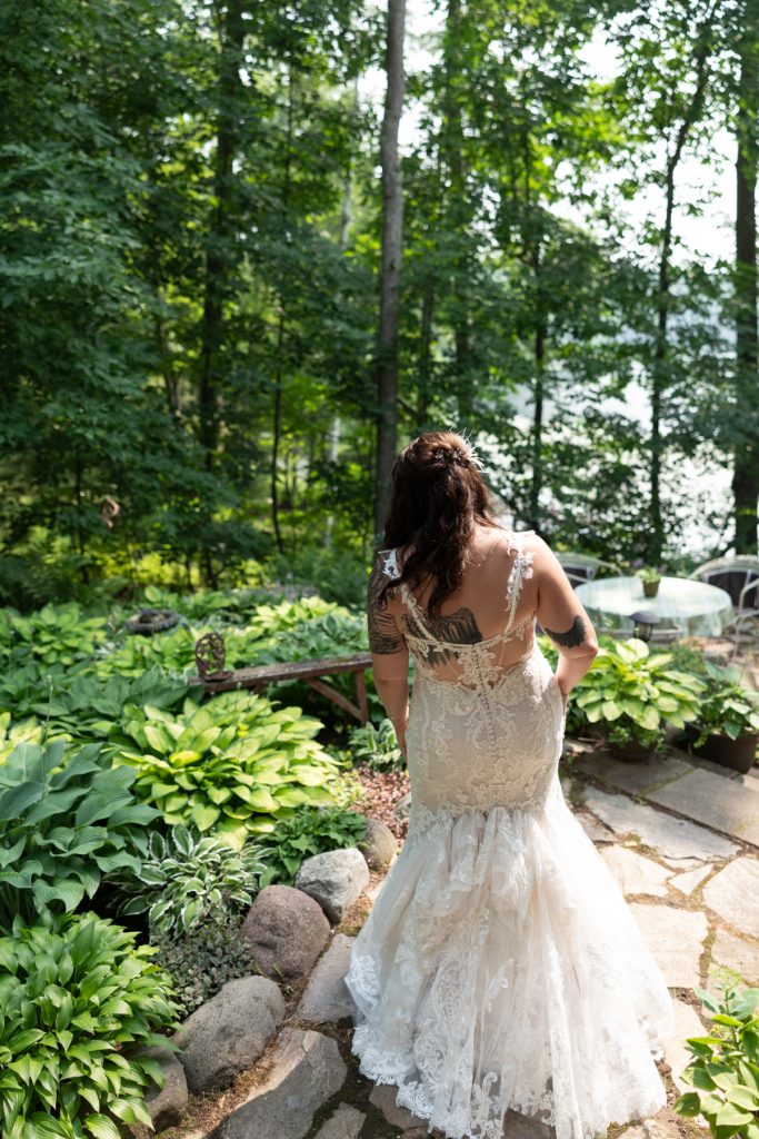Bride in wedding dress walking toward lake ceremony at Hayward, WI cabin wedding