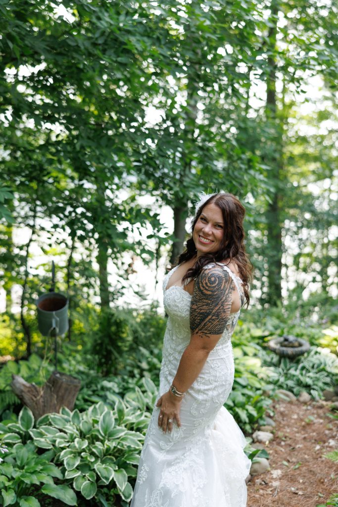 Bride in wedding dress smiling in lakeside backyard wedding setting in Hayward, WI