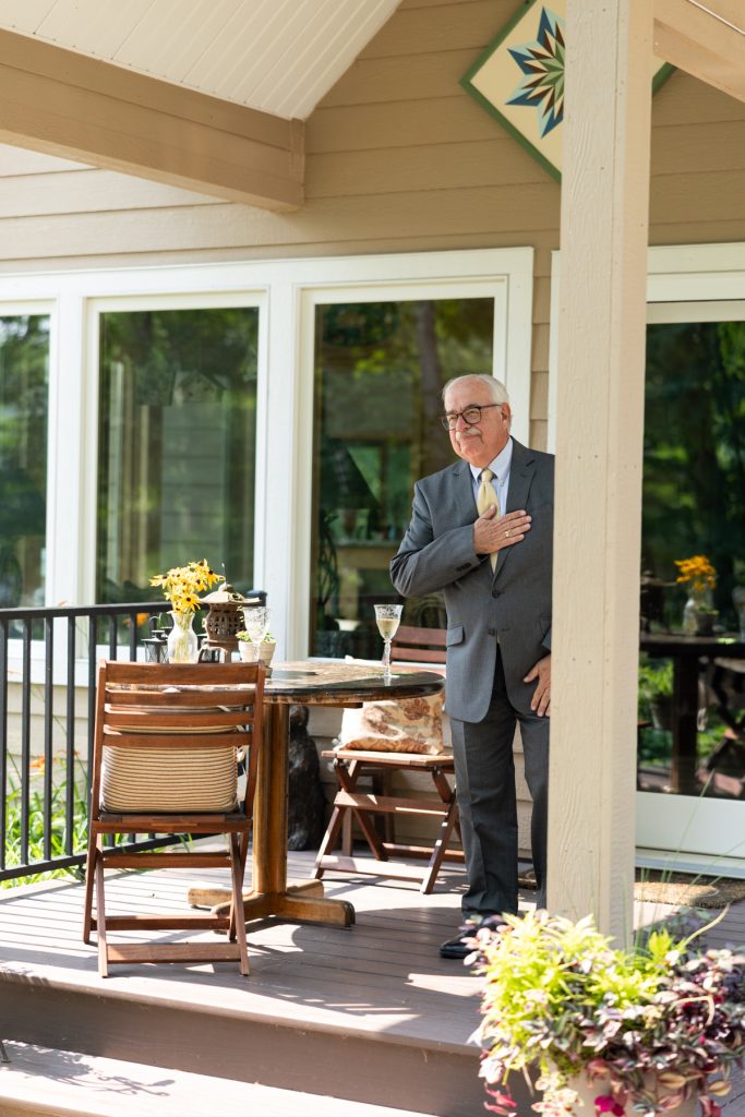 Groom in suit standing near lakefront cabin during Hayward, WI wedding ceremony.