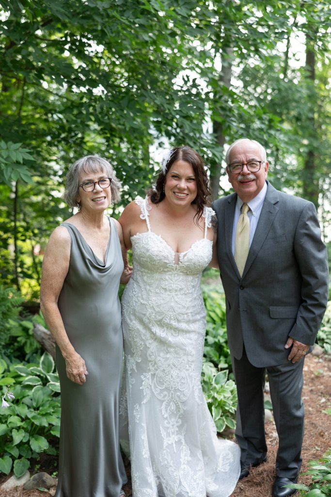 Bride with parents at Hayward, WI wedding ceremony in a family cabin setting.