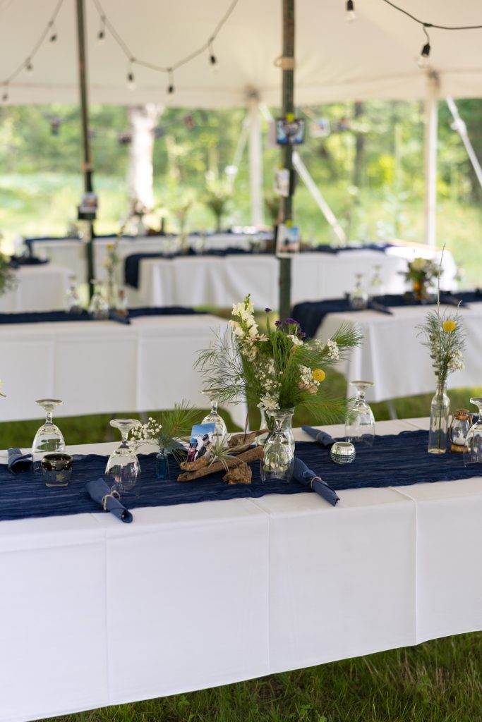 Wedding reception tables decorated with flowers and blue linens at a lakeside cabin in Hayward,