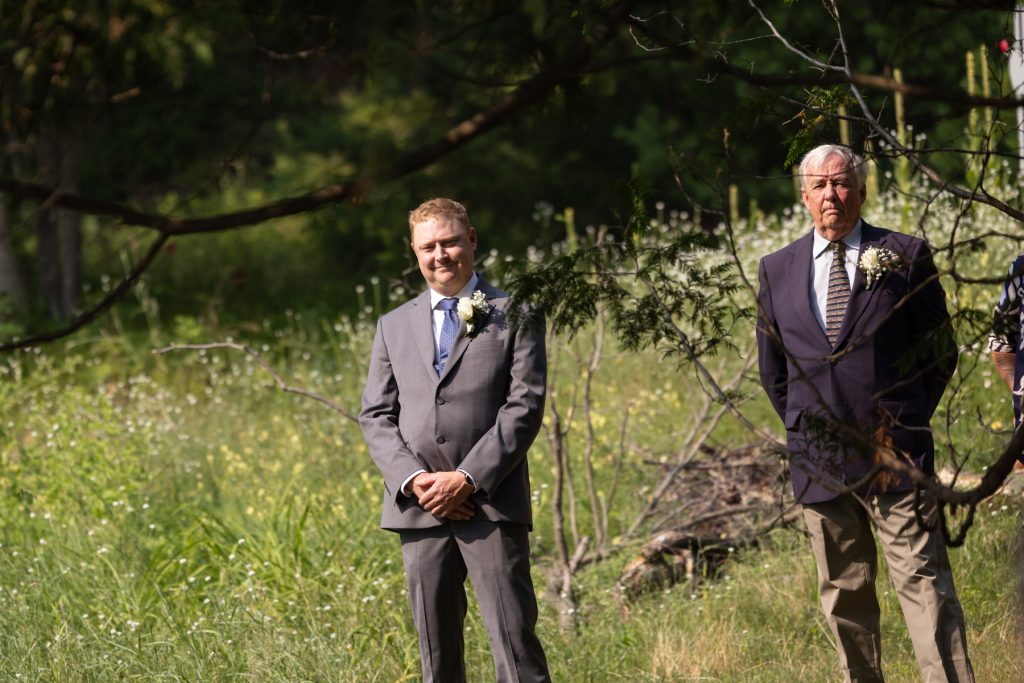 Groom and father in suits at lakeside wedding in Hayward, WI.