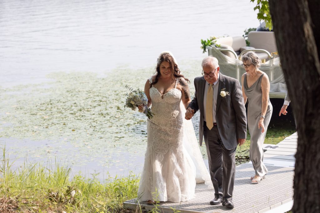 Bride and father walking on dock towards lake ceremony in Hayward, WI