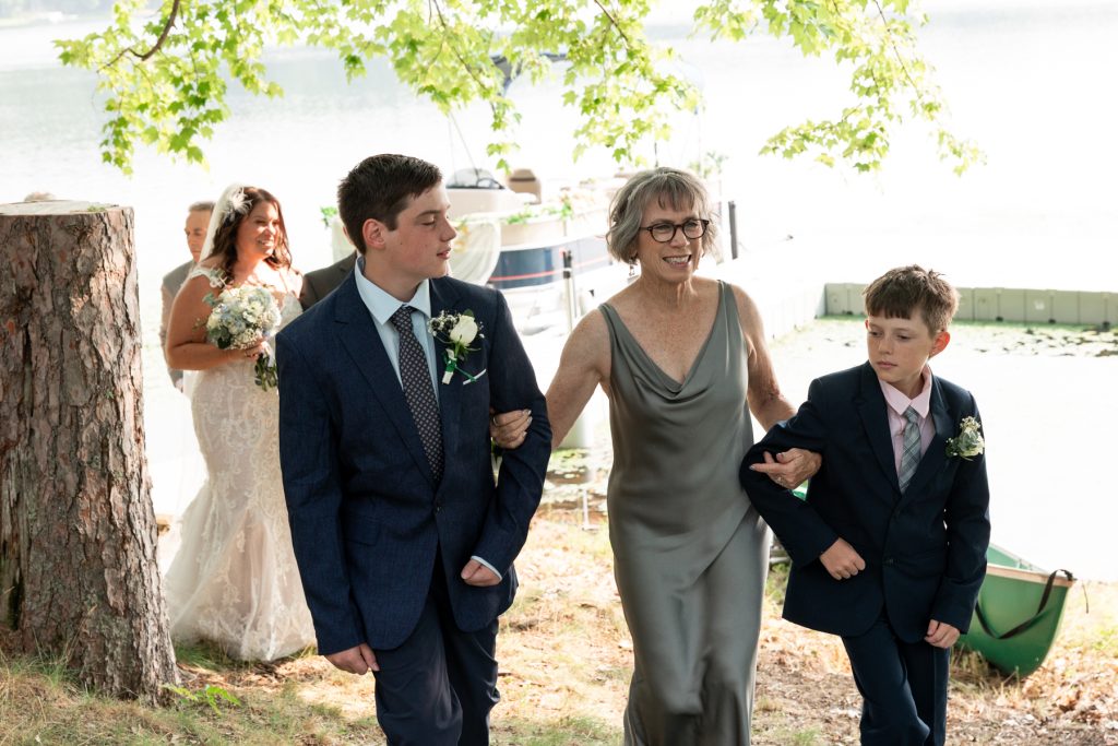 Bride and family members walking towards lake-side ceremony in Hayward, WI.