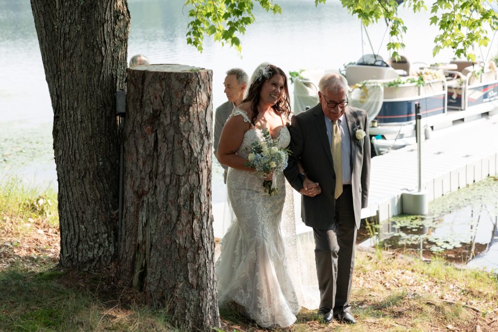 Bride and father walking down aisle at lakefront wedding in Hayward, WI