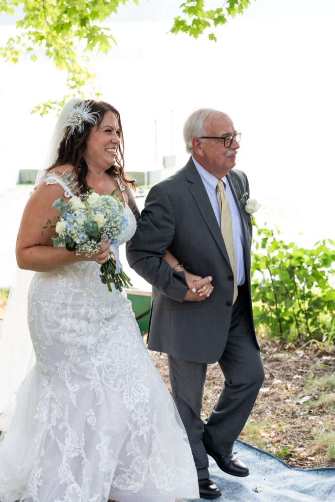 Bride and father walking down aisle at lake-side wedding in Hayward, WI
