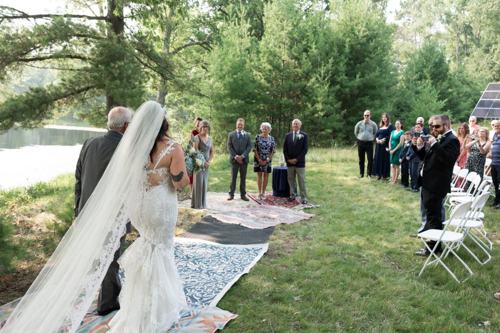 Bride walking down aisle towards lake ceremony at Hayward, WI wedding