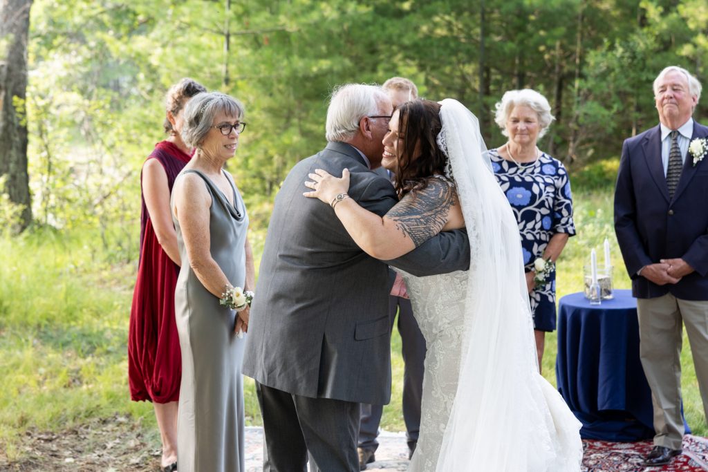 Bride and groom embracing at lakeside wedding ceremony in Hayward, WI